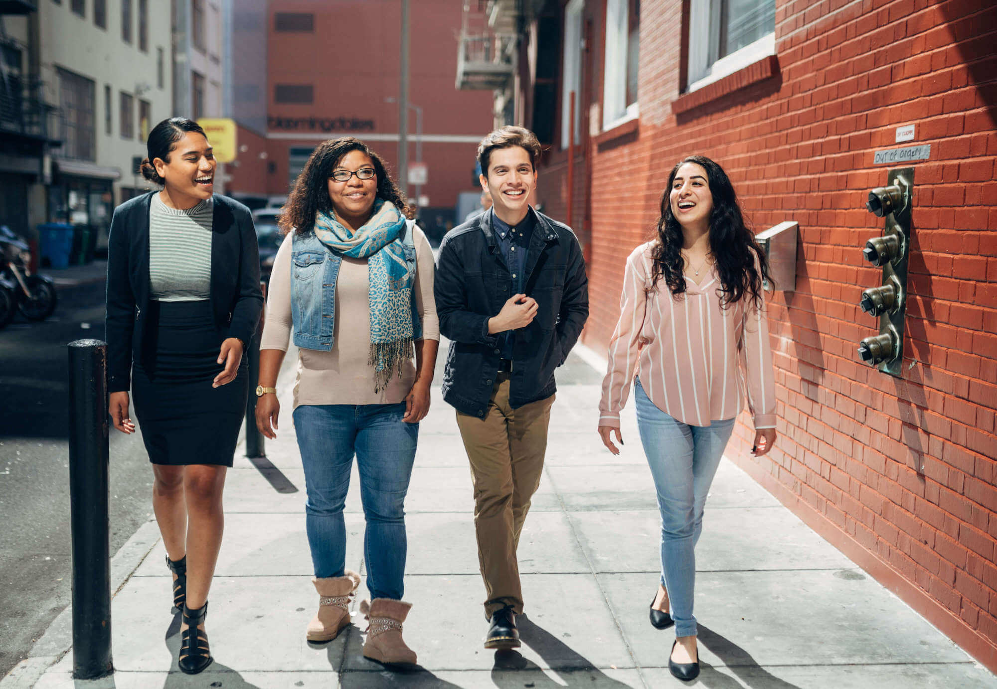 Four young people walking along a sidewalk