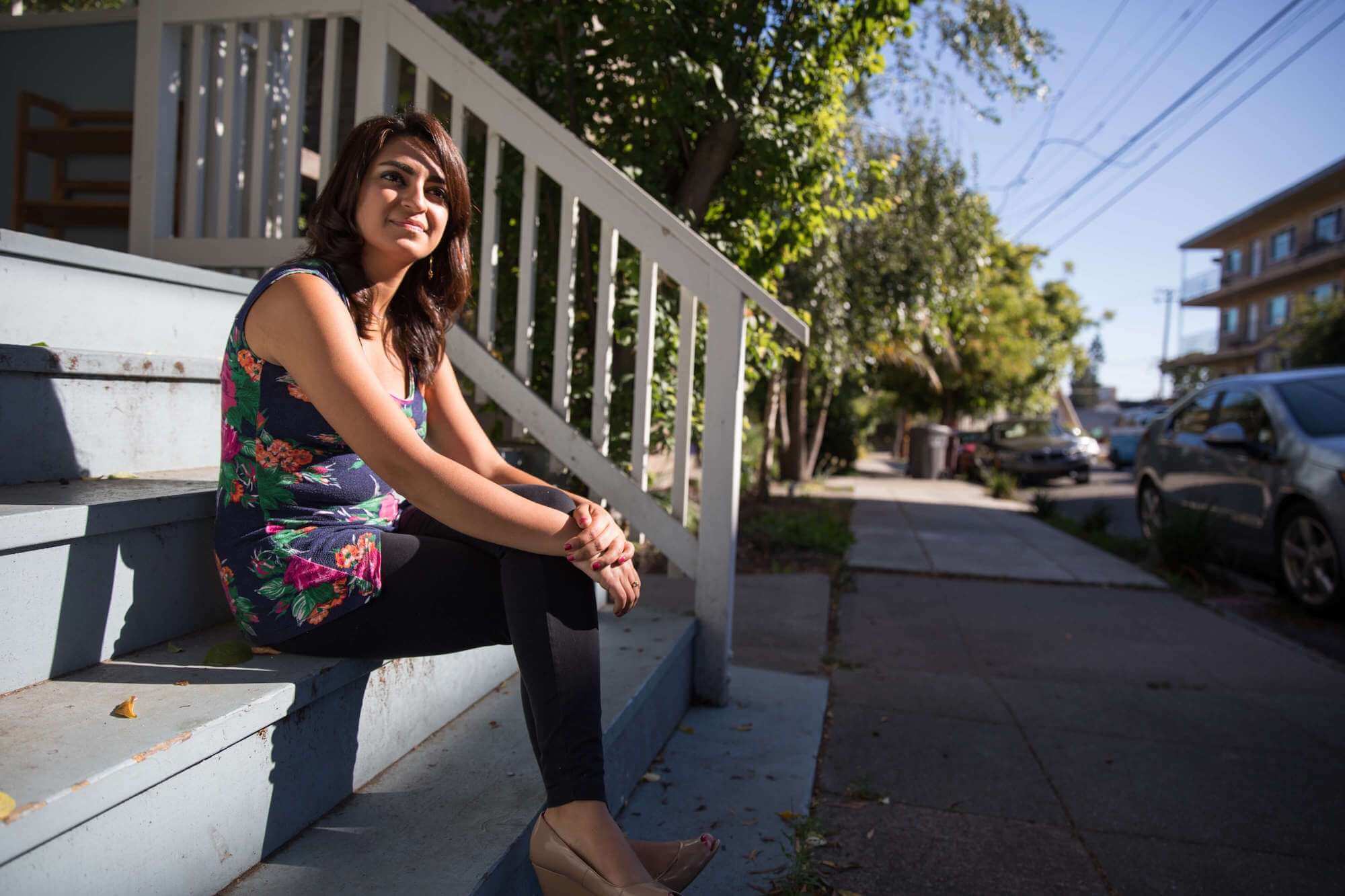 Smiling woman sitting on steps in front of her home